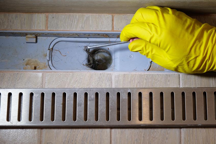 plumber removing clogged shower drain