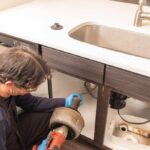 Plumber using an electric snake to unclog a kitchen sink