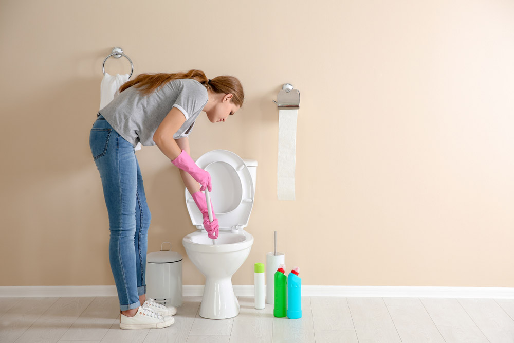 Woman cleaning clogged toilet Staunton, VA