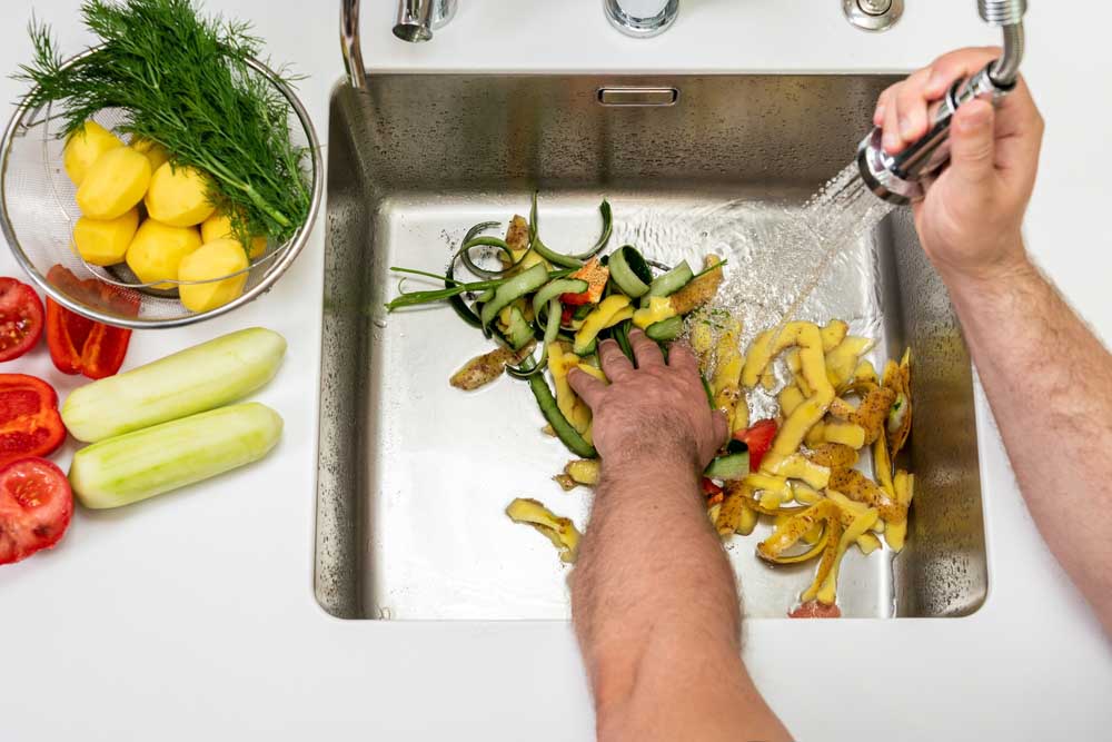 a person using the garbage disposal in the kitchen sink a person using the garbage disposal in the kitchen sink