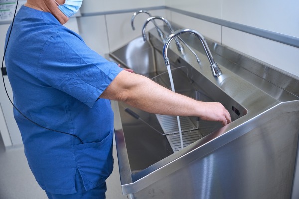 healthcare worker using commercial handwashing sink